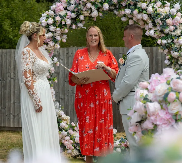 Wedding moment 2: Lesley Coles leading an outdoor ceremony under a flower arch